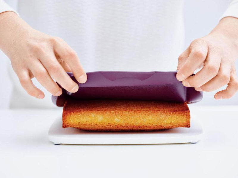 person removing cake from the tupperware silicone rectangular form