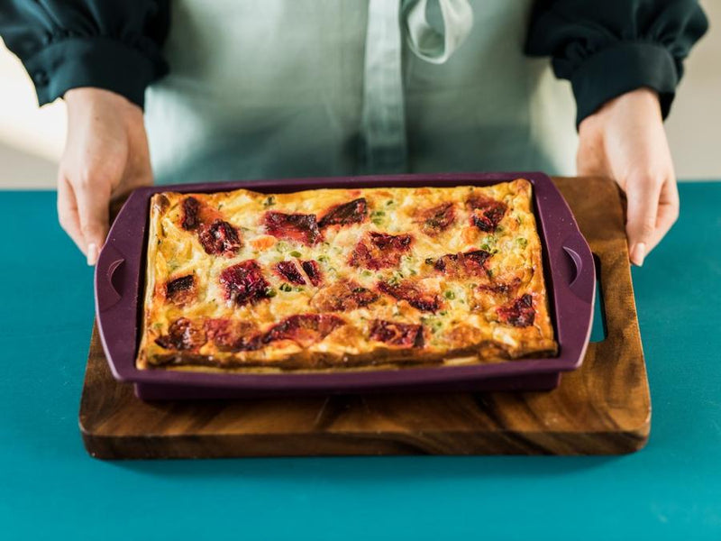 person serving quiche in a tupperware silicone rectangular form